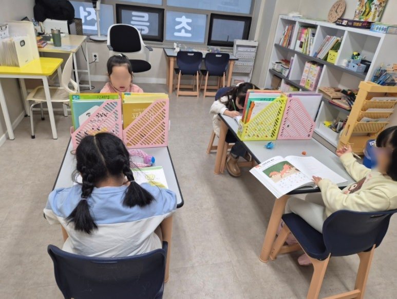 공부하는코끼리수학 초등 1~2학년 교실. 아이들이 각자 다른 교재를 펼쳐 놓고 개별 진도로 공부하고 있으며, 책상마다 학습 가림판과 교구가 놓여 있다.